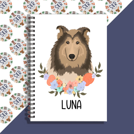 A notebook with a spiral binding featuring a graphic of a Rough Collie dog on the front cover, with a floral design on the spine.
