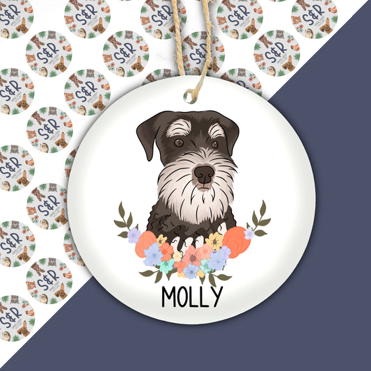 A ceramic Christmas decoration featuring an illustration of a Schnauzer dog with a floral wreath background, with the name 'Molly' underneath.