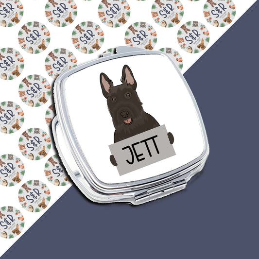 A personalised compact mirror with an image of a Scottish Terrier dog and the name 'Jett' on the front, surrounded by a pattern of the same dog breed.