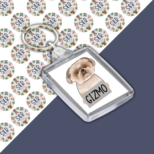 A personalised keyring featuring an illustration of a Shih Tzu dog on a round, clear acrylic casing with a custom name 'Gizmo' printed on it.