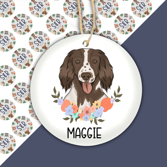 A ceramic springer spaniel dog Christmas bauble with a floral pattern and the name 'Maggie' inscribed on the front.
