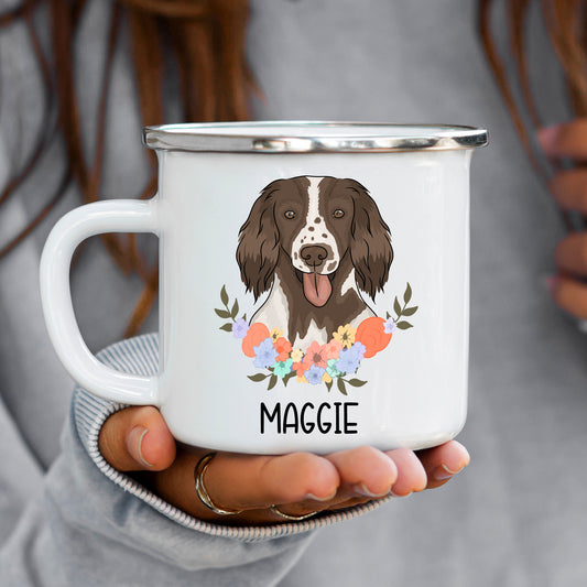 A white enamel mug with a graphic of a Springer Spaniel dog breed, surrounded by a floral pattern, with the name 'Maggie' inscribed on the mug.