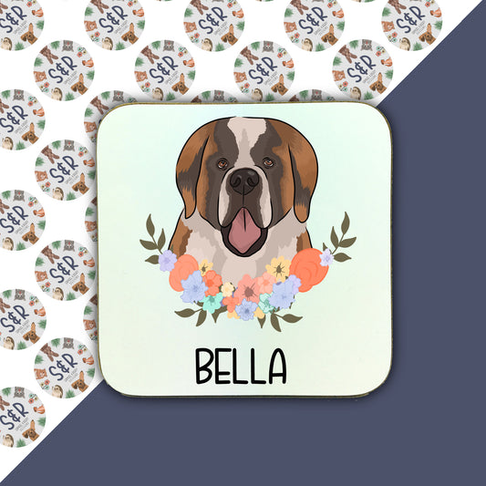 A square coaster with an illustration of a Saint Bernard dog surrounded by a floral wreath. The coaster has a glossy finish and the text 'Bella' is visible at the bottom.