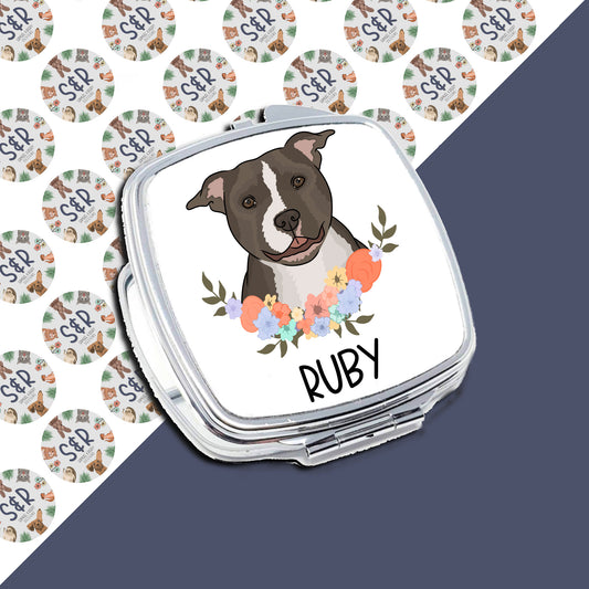 A personalised compact mirror with an illustration of a dog breed, presumably a Staffy, surrounded by a floral pattern. The mirror has a glossy finish and includes the name 'Ruby'.
