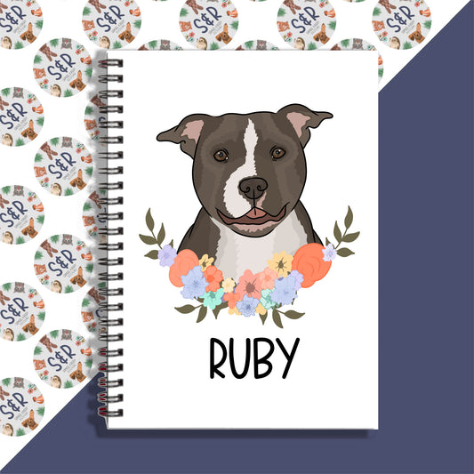 A personalised notebook with a spiral binding featuring an illustration of a dog on the front cover, with the name 'Ruby' written on the notebook.