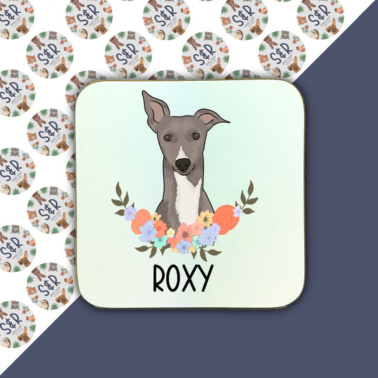 A square coaster with a illustration of a Whippet dog surrounded by a floral pattern, with the name 'Roxy' at the bottom.